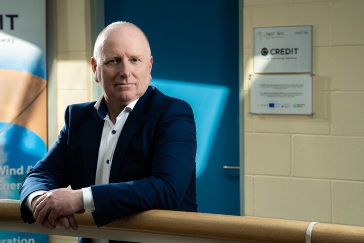 Photo of Shane Reenan in dark suit jacket lean on banister